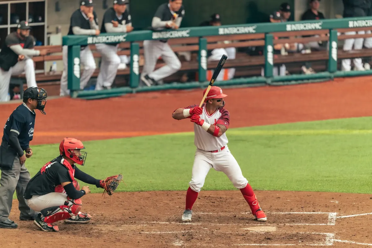 Baseball player poised to swing the bat during an exciting game, with catcher and umpire nearby.